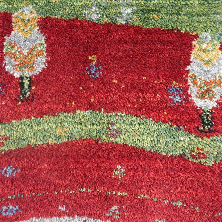 赤と緑の色彩が鮮やかな手織りのギャッベラグには、ウールの温かみとともにペルシャ絨毯ならではの繊細な模様が際立っている。
