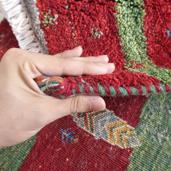 手織りのギャッベラグが丁寧に折り返され、ウールの温かみや豊かな色彩が指先に伝わるように感じられる。