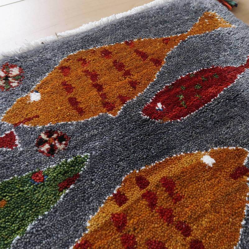 手織りのウール素材が温かみを感じさせるギャッベのラグは、色鮮やかな魚の模様が印象的で、ペルシャ絨毯専門店の通販で手に入る一品です。