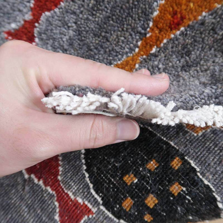 手で持ち上げられたギャッベのラグは、手織りの技術が光る厚みとウールの素材感が感じられ、ペルシャ絨毯の専門店で通販可能な逸品が垣間見える。