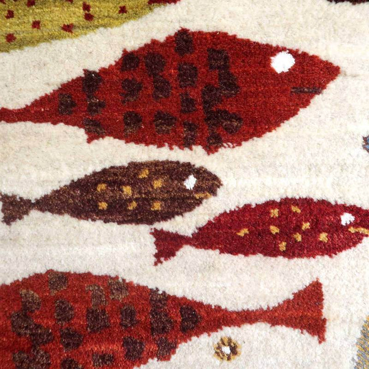赤や茶の魚柄が丁寧に織り込まれた手織りのギャッベラグが、ペルシャ絨毯専門店の通販で見つかります。
