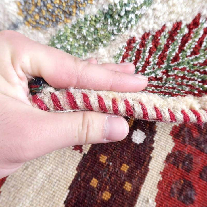 手織りのギャッベラグの厚みと織り目の細かさを指で触れて確認できる様子が見える。