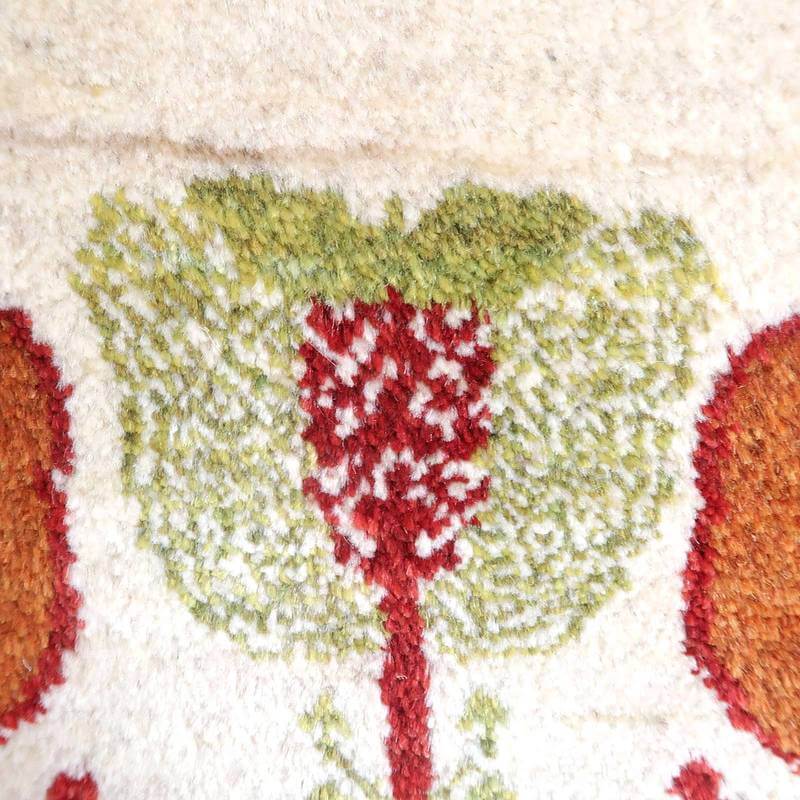 手織りのギャッベラグが、緑と赤の花模様で丁寧に織られており、ウールの柔らかな質感が際立っている。