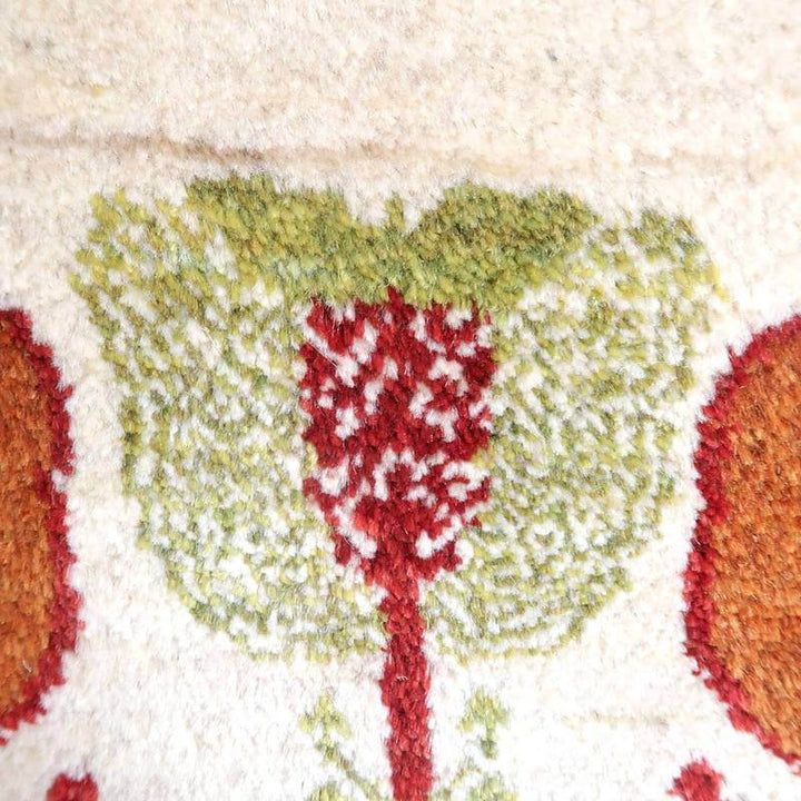 手織りのギャッベラグが、緑と赤の花模様で丁寧に織られており、ウールの柔らかな質感が際立っている。