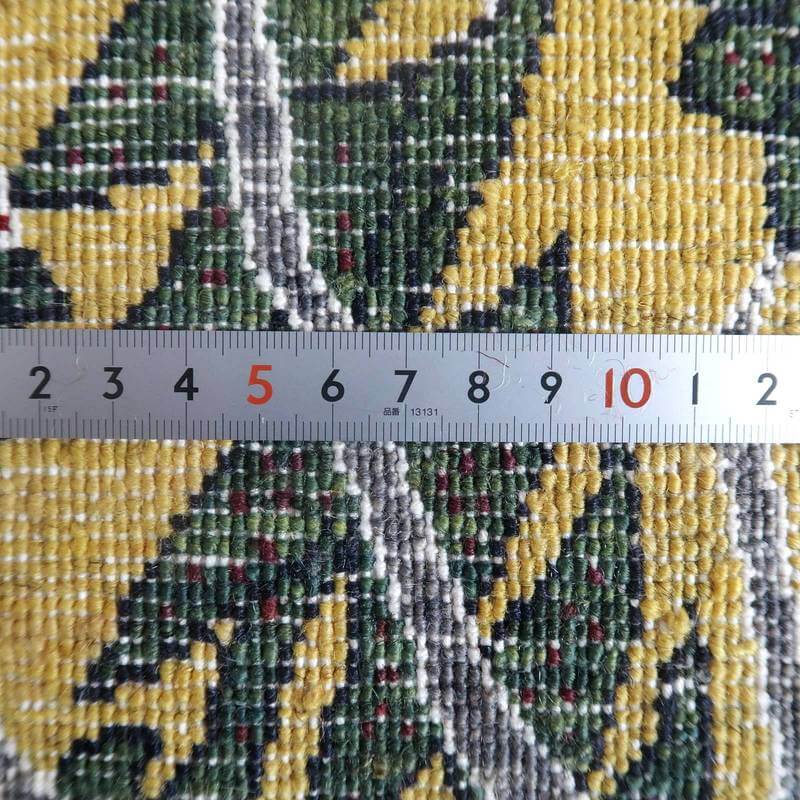 緻密に手織りされたペルシャ絨毯専門店のウール製ギャッベの模様と織りの密度が定規とともに確認できる。