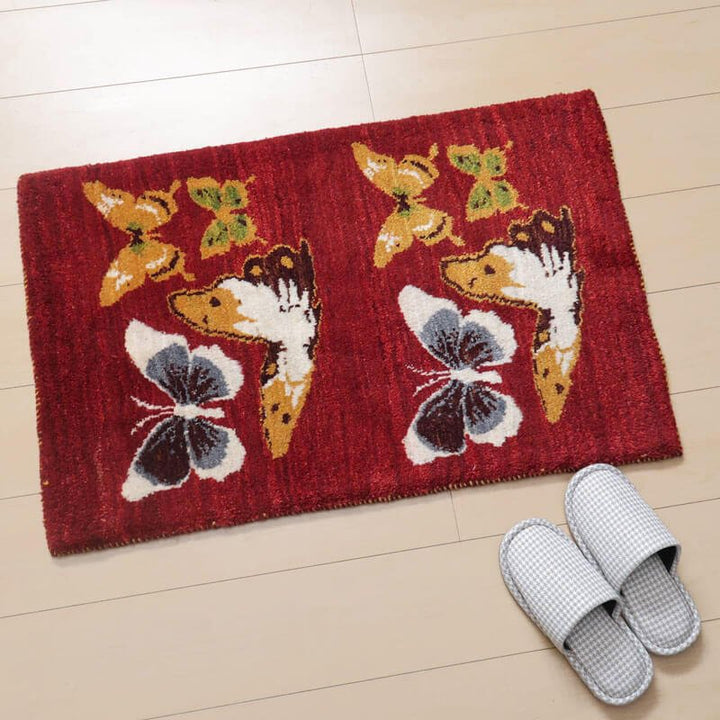 赤い背景に蝶のデザインが施された手織りのギャッベが玄関に敷かれている。