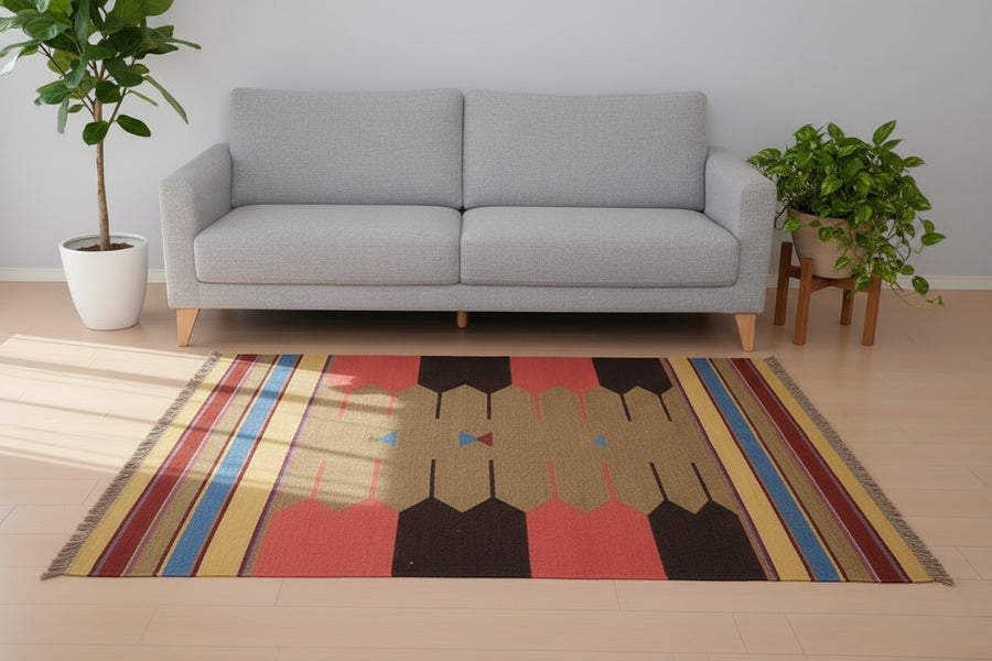 赤いソファの前に敷かれた手織りのウール製ギャッベラグが、ペルシャ絨毯専門店の通販で購入できる。