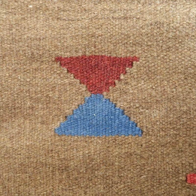 赤と青の三角模様が特徴的な、手織りのギャッベラグのウール素材が接写で見える。