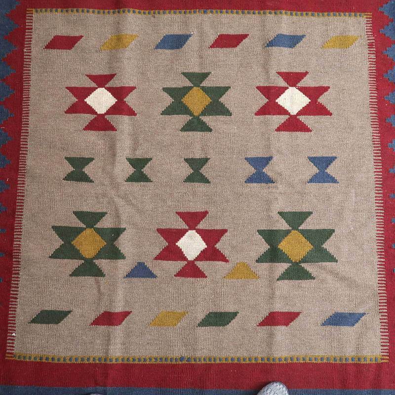 伝統的なペルシャ絨毯専門店が通販する、手織りウール製ギャッベラグが床に広がり、鮮やかな幾何学模様が際立っている。