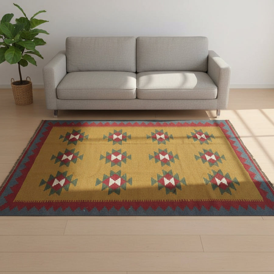 赤いソファの前に広がる、ペルシャ絨毯の専門店通販で手織りされたウール製ギャッベラグが、幾何学模様と温かな色合いでリビングルームに落ち着きを与えている。