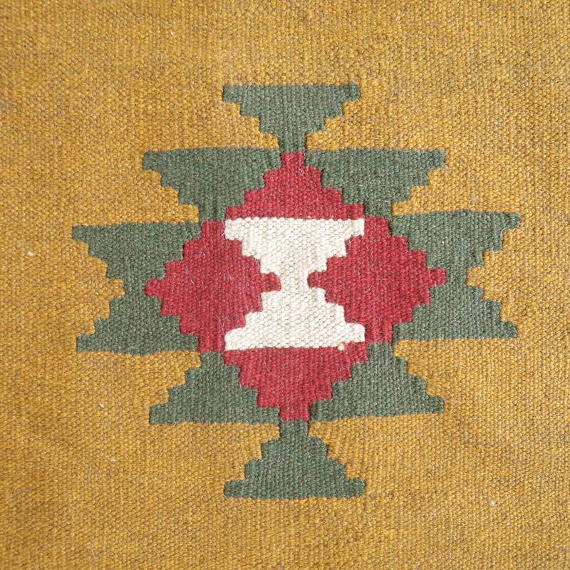 赤と緑の幾何学模様が中央に配置された、手織りのウール製ギャッベラグが床に敷かれている。