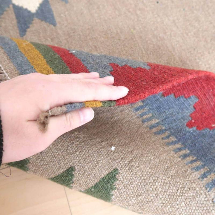 手織りのギャッベラグの裏面がめくられ、ウールの柔らかな質感とペルシャ絨毯の豊かな色彩が際立っています。