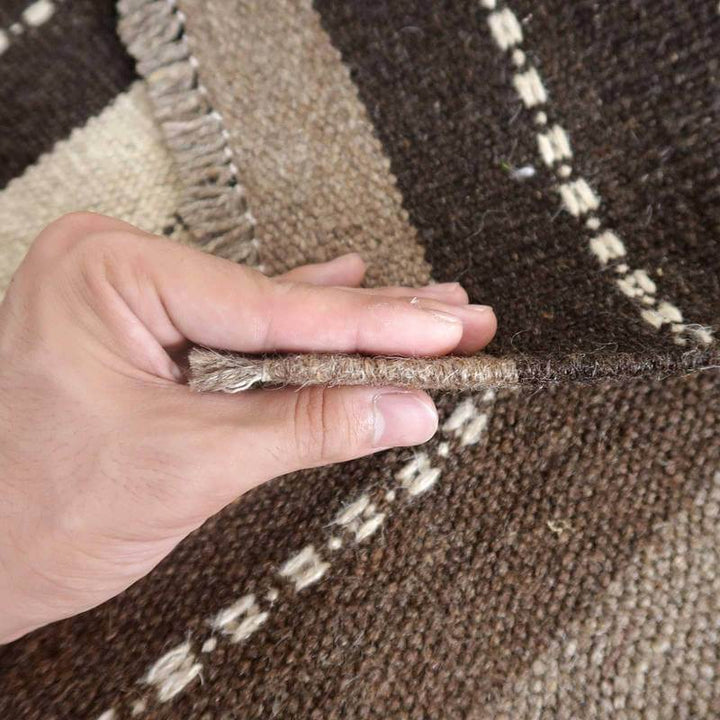 手織りのウール製ギャッベラグが持ち上げられ、織り目の密度と厚みが際立っている。