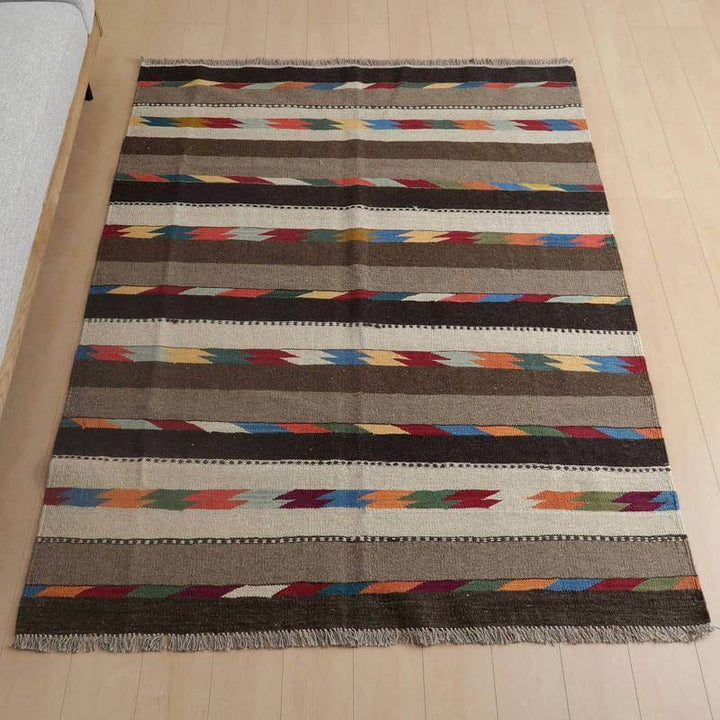 キリム・シラーズ／カシュガイ 203×154cm（KL-796）は、色とりどりのストライプ模様が特徴の手織りウール製ギャッベラグが、木目の床にぴったりと敷かれている。