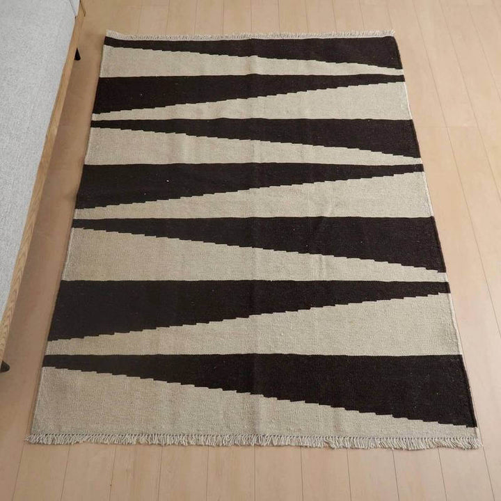キリム・シラーズ／カシュガイ 205×153cm（KL-799）は、黒とベージュのコントラストが美しい幾何学模様の手織りウールギャッベラグが、リビングの床に敷かれている。