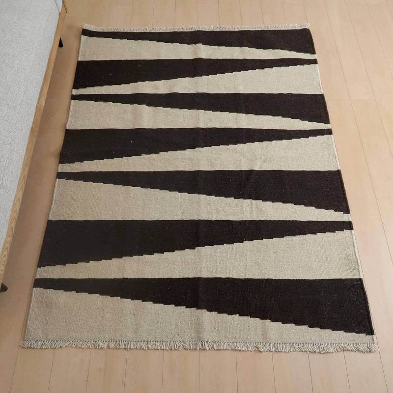 キリム・シラーズ／カシュガイ 205×153cm（KL-799）は、黒とベージュのコントラストが美しい幾何学模様の手織りウールギャッベラグが、リビングの床に敷かれている。