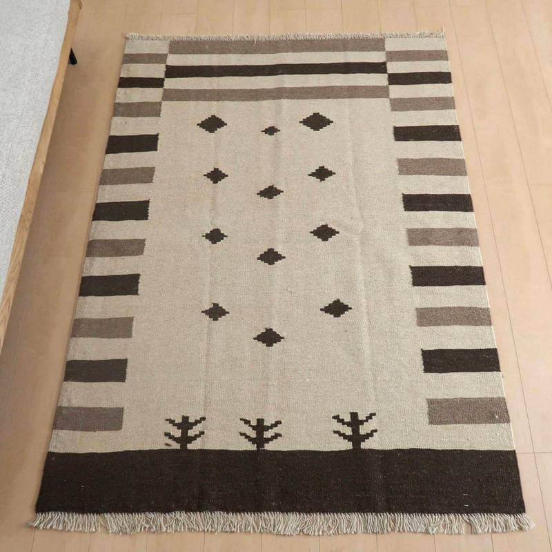 キリム・シラーズ／カシュガイ 180×132cm（KL-865）は、ベージュとブラウンの幾何学模様が特徴の手織りウールギャッベラグが、ペルシャ絨毯専門店の通販で床に敷かれている。