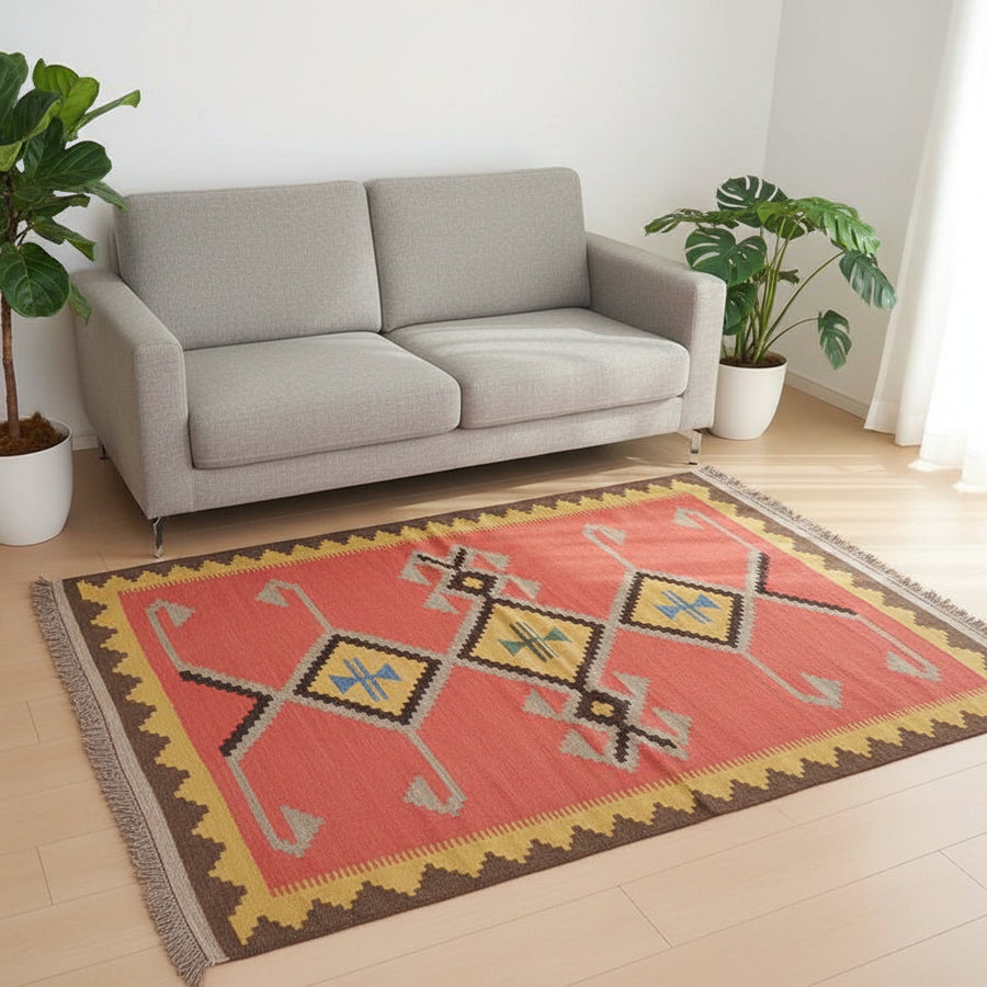 赤いレザーソファの前に、鮮やかな幾何学模様が印象的な手織りのギャッベラグが床に敷かれている。