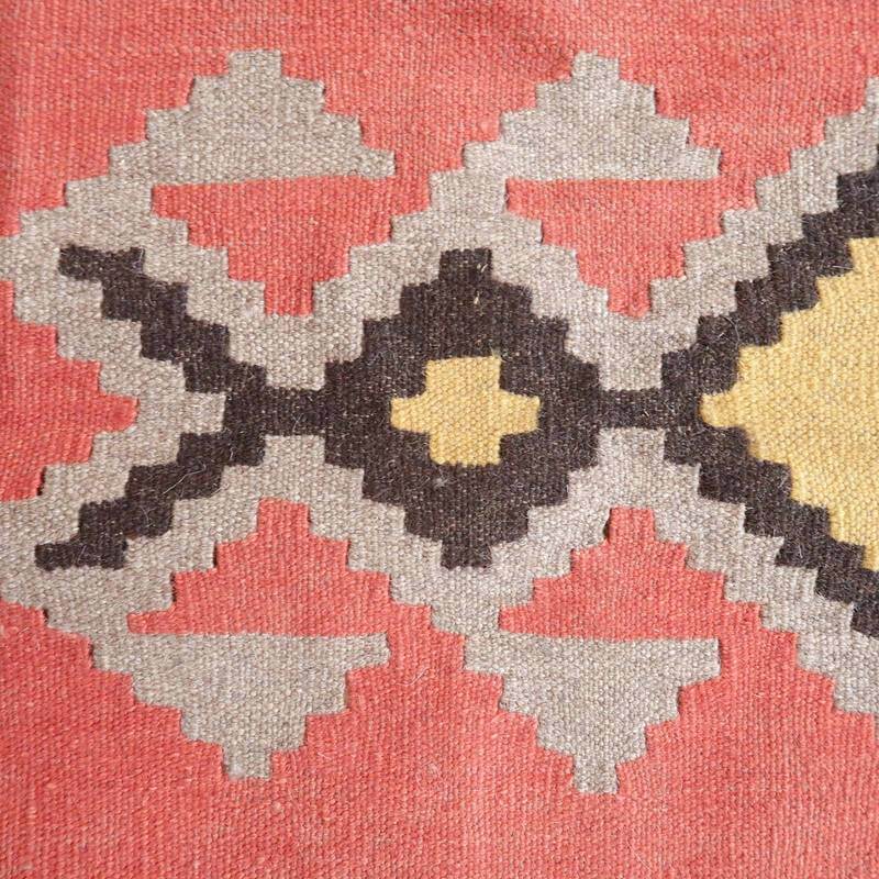 鮮やかな赤と黄色の幾何学模様が特徴的な手織りのギャッベラグは、ウール素材の温かみが感じられる一品です。