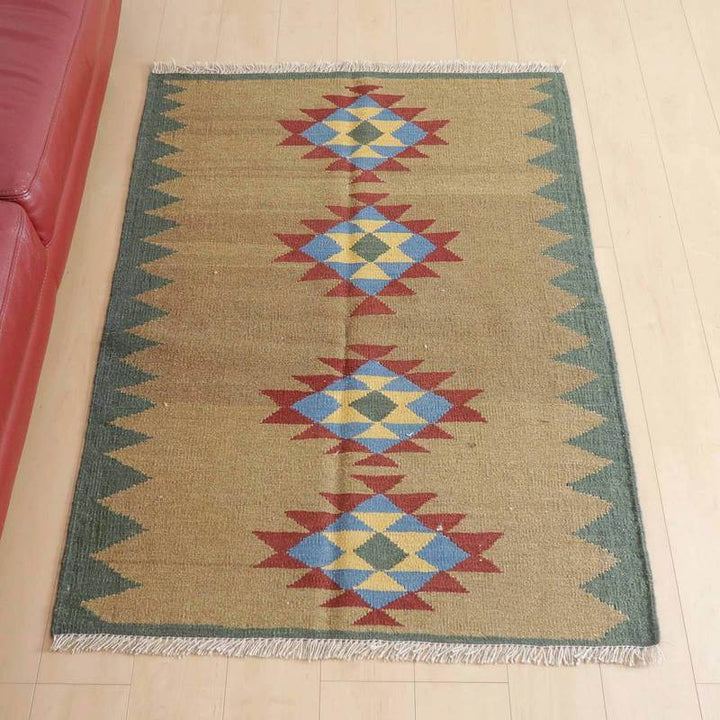 キリム・シラーズ／カシュガイ 141×103cm（KM-419）は、赤と青の幾何学模様が際立つ手織りのウール製ギャッベラグが、シンプルな木目床にしっかりと敷かれている。