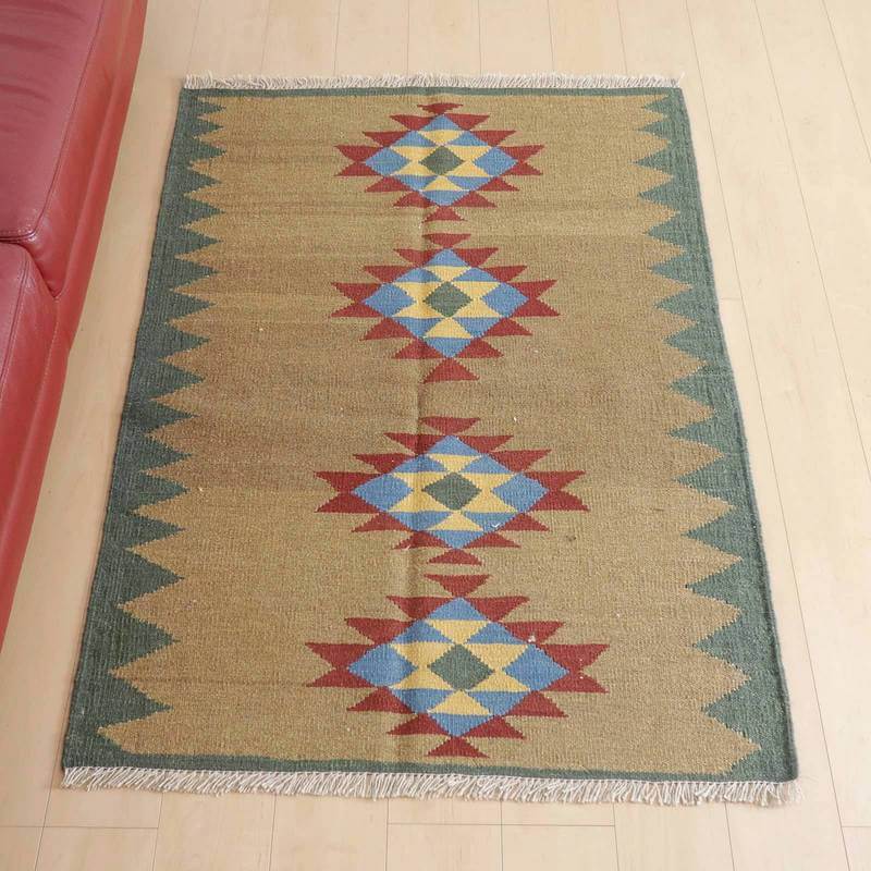 キリム・シラーズ／カシュガイ 141×103cm（KM-419）は、赤と青の幾何学模様が際立つ手織りのウール製ギャッベラグが、シンプルな木目床にしっかりと敷かれている。