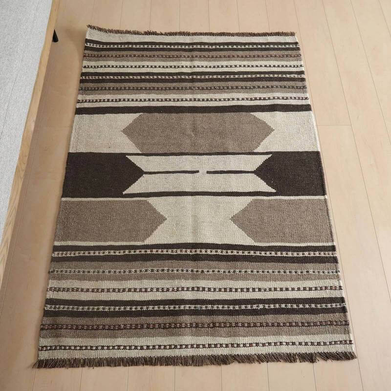 キリム・シラーズ／カシュガイ 149×105cm（KM-818）は、手織りのウール素材で作られたギャッベラグがペルシャ絨毯専門店の通販で購入可能で、シンプルな幾何学模様が木製フローリングの上に美しく敷かれている。