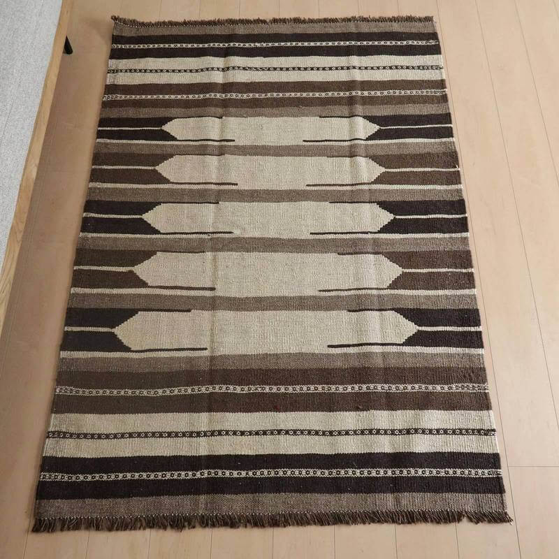 キリム・シラーズ／カシュガイ 171×120cm（KM-820）は、手織りのウール製ギャッベラグが、玄関のフローリングに自然に調和し、ペルシャ絨毯の伝統的な美しさが際立っている。