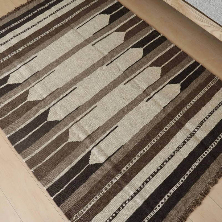 手織りのウール素材で丁寧に作られたギャッベラグが、ペルシャ絨毯専門店から通販され、シンプルな幾何学模様が床に調和している。