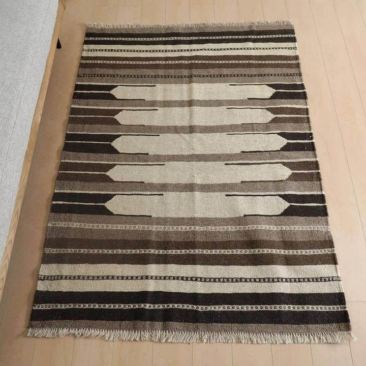 キリム・シラーズ／カシュガイ 174×125cm（KM-823）は、手織りのぬくもりが伝わるウール素材のギャッベラグが、リビングルームの床に自然に溶け込み、シンプルで落ち着いた模様が際立っている。