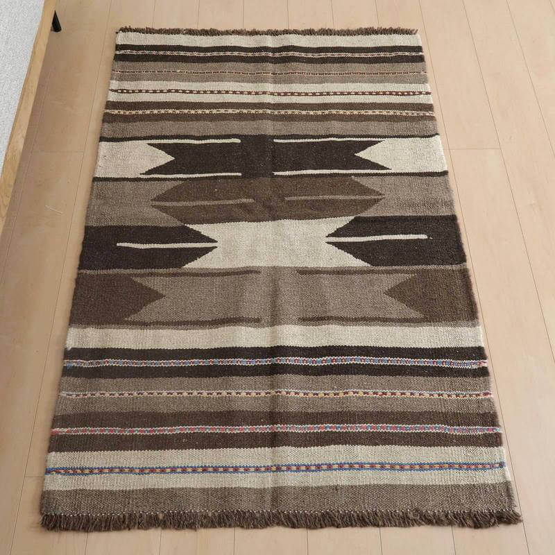 キリム・シラーズ／カシュガイ 151×99cm（KM-828）は、手織りのギャッベラグが玄関に敷かれており、ブラウンとベージュの落ち着いた模様が床の上で調和し、ウールの温かみが感じられます。