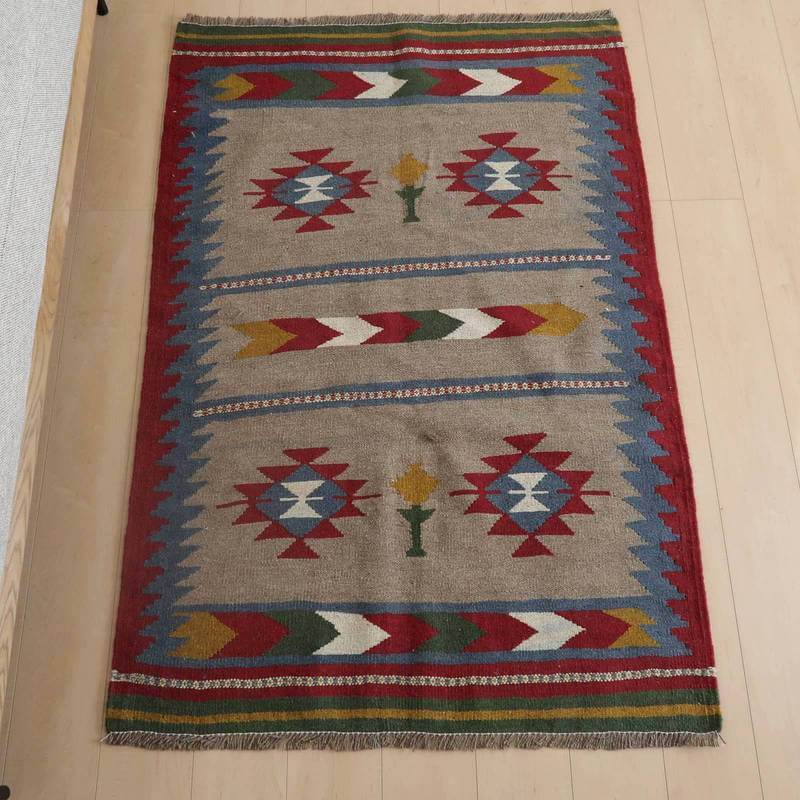 キリム・シラーズ／カシュガイ 150×100cm（KM-835）は、手織りの温もりを感じるペルシャ絨毯専門店のギャッベラグが、鮮やかな幾何学模様と深みのあるウールの色合いで床に置かれている。