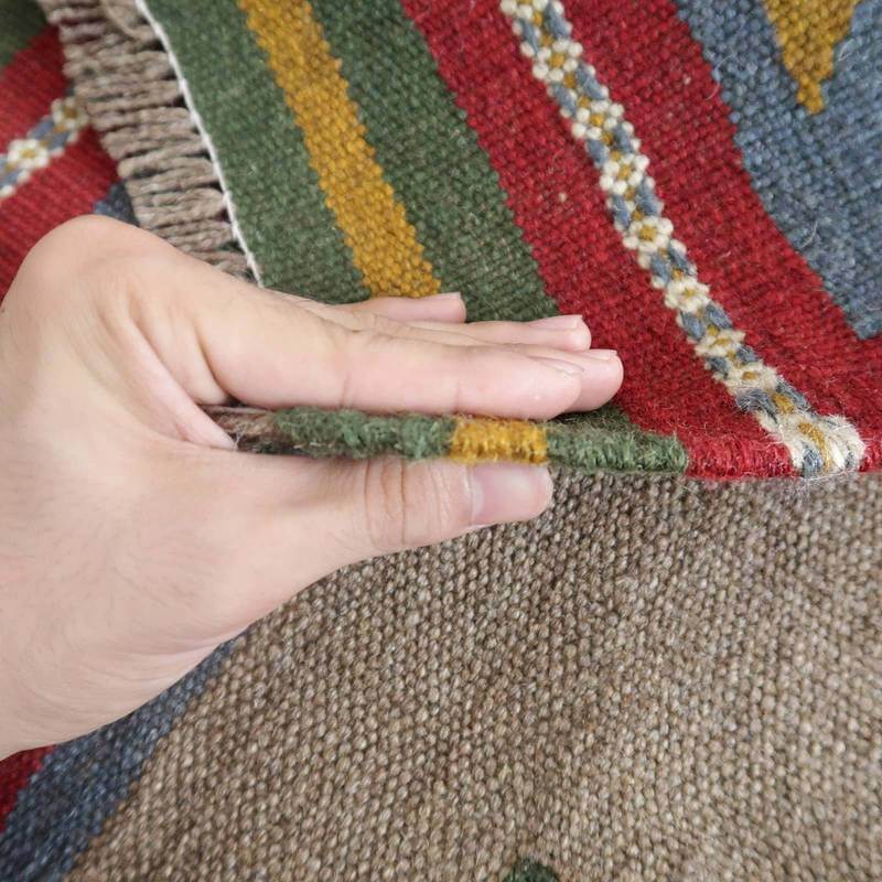 この手織りのギャッベラグは、ウールの厚みがしっかりしており、鮮やかな色合いが重なり合うペルシャ絨毯の魅力が指先に感じられる。