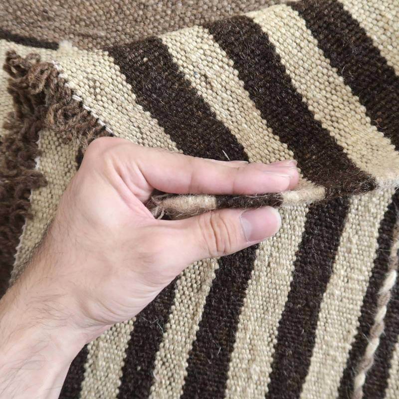 手織りのギャッベラグの厚みを確認するために持ち上げられた部分のウール素材が、ペルシャ絨毯専門店の丁寧な手仕事を感じさせます。