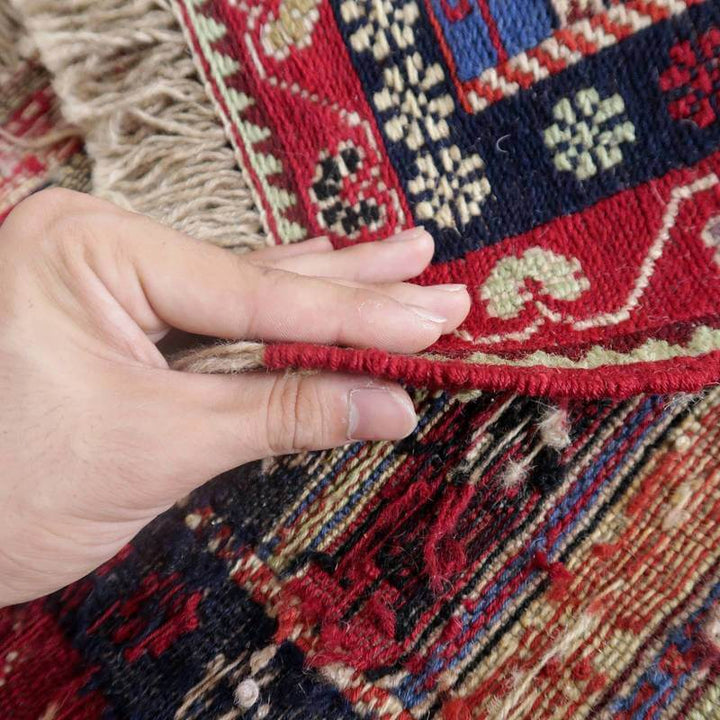手でめくられたペルシャ絨毯のギャッベが、ウールの手織り模様を際立たせながら、通販専門店の魅力を伝えている。
