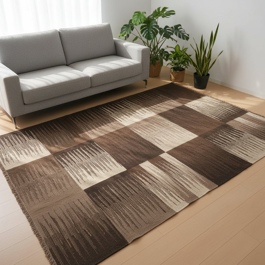 茶色とベージュの市松模様が印象的な手織りのウール製ギャッベラグが、赤いソファの前に広がり、リビングに温かみを添えている。