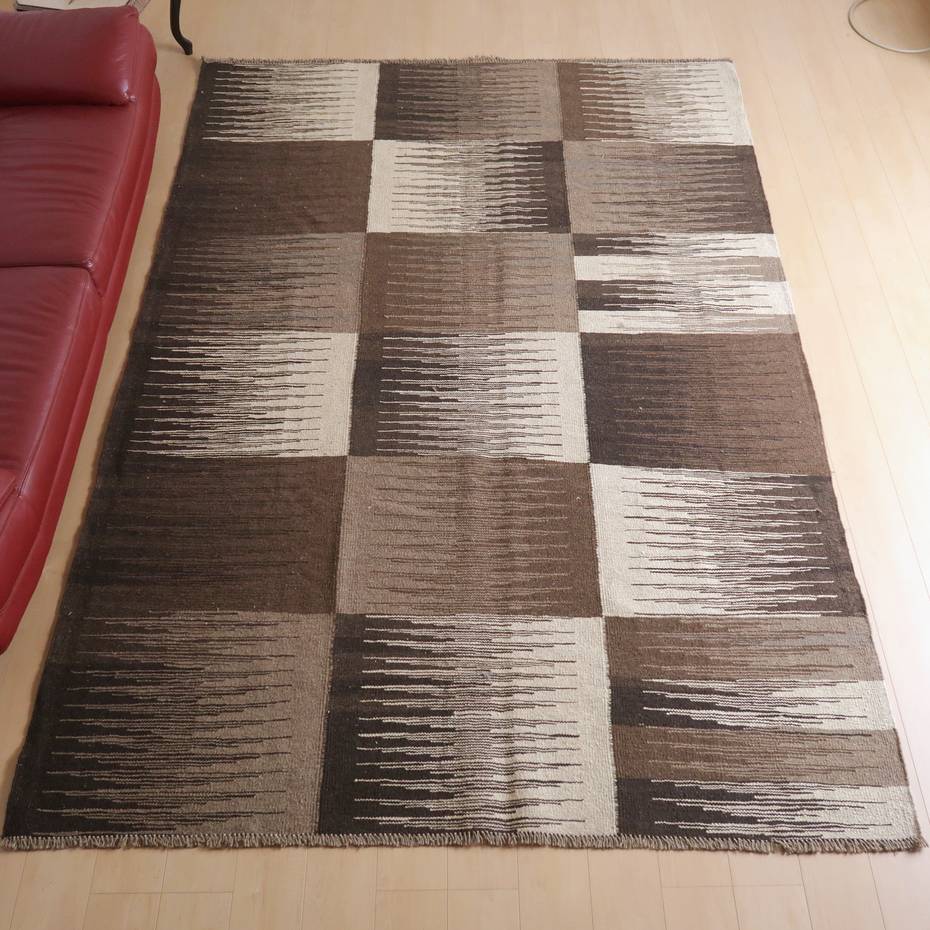 キリム・シラーズ／カシュガイ 297×202cm（KX-66386）は、幾何学模様のブラウンとベージュが織りなす手織りのギャッベラグが、温かみのあるリビングの床に敷かれている。