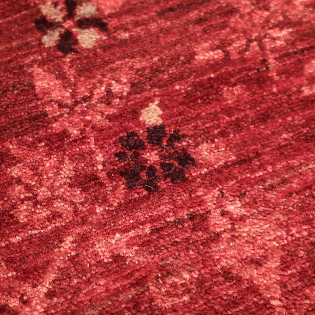 深紅の織物に薄いピンクと濃い茶色の小さな花模様が散りばめられている布地の拡大写真