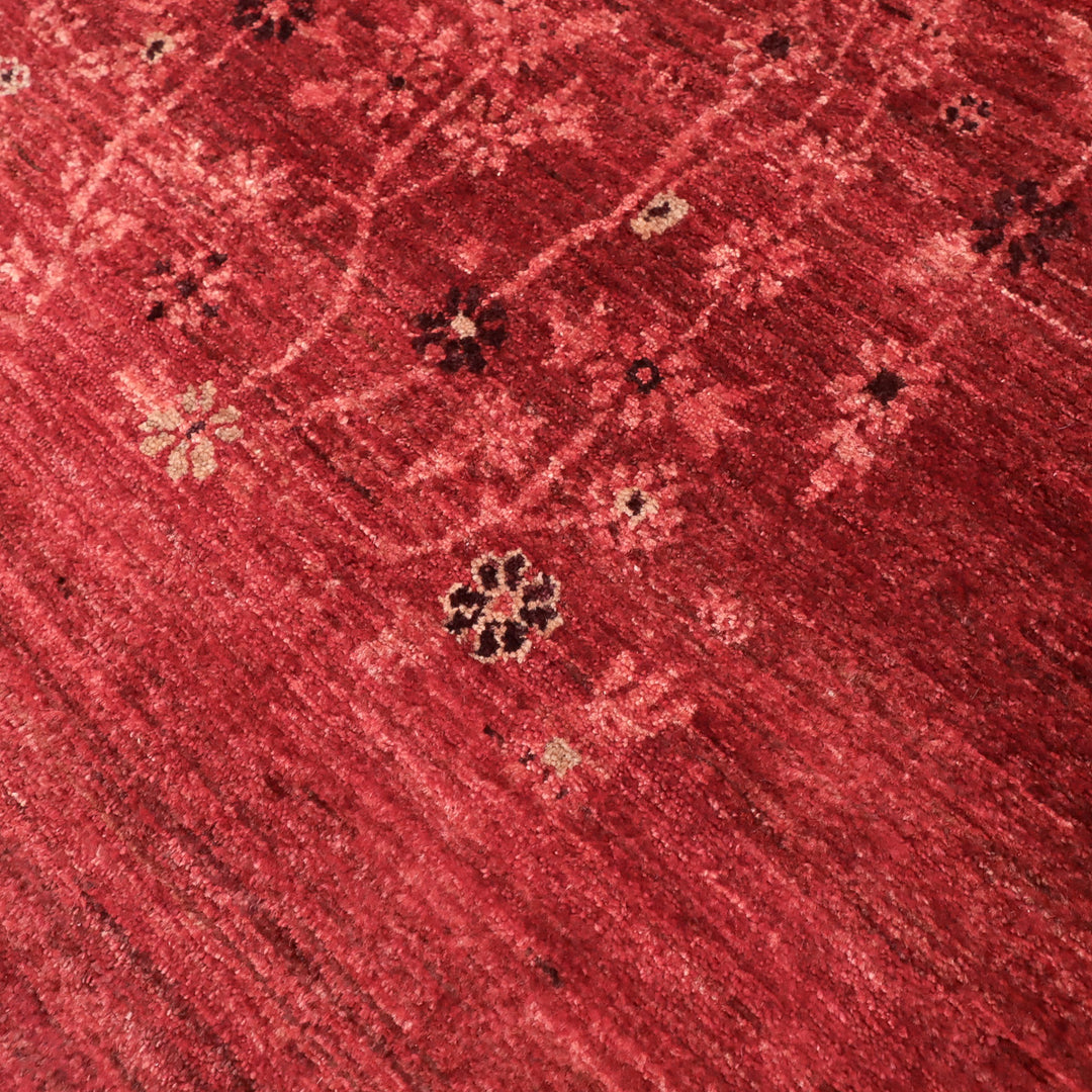 赤い背景に繊細な花柄が描かれたテクスチャのある織物の一部のクローズアップ画像