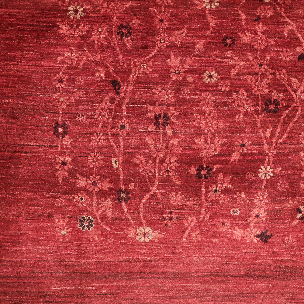 赤い背景に淡い色の枝と小花が織り込まれた繊細な模様の布地の一部。