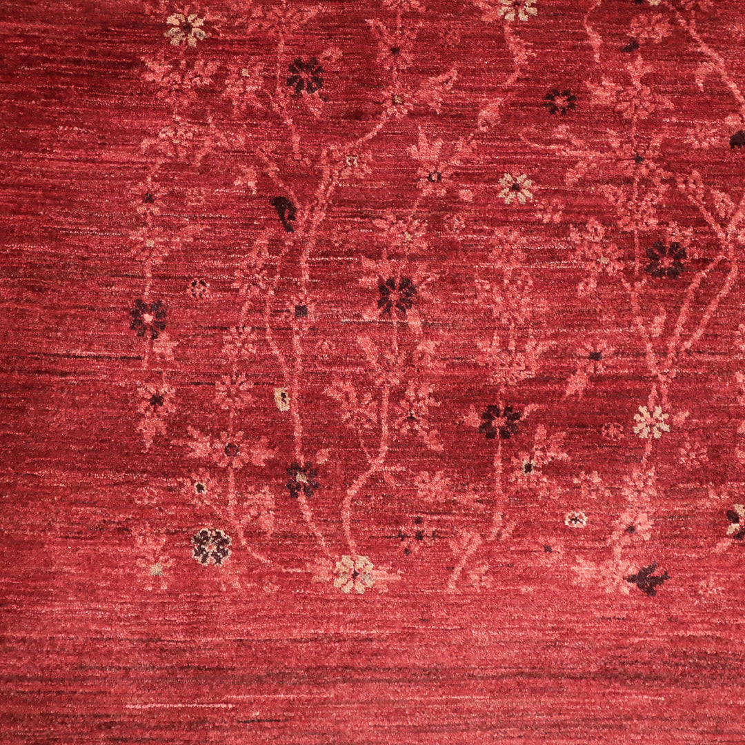 赤い背景に淡い色の枝と小花が織り込まれた繊細な模様の布地の一部。