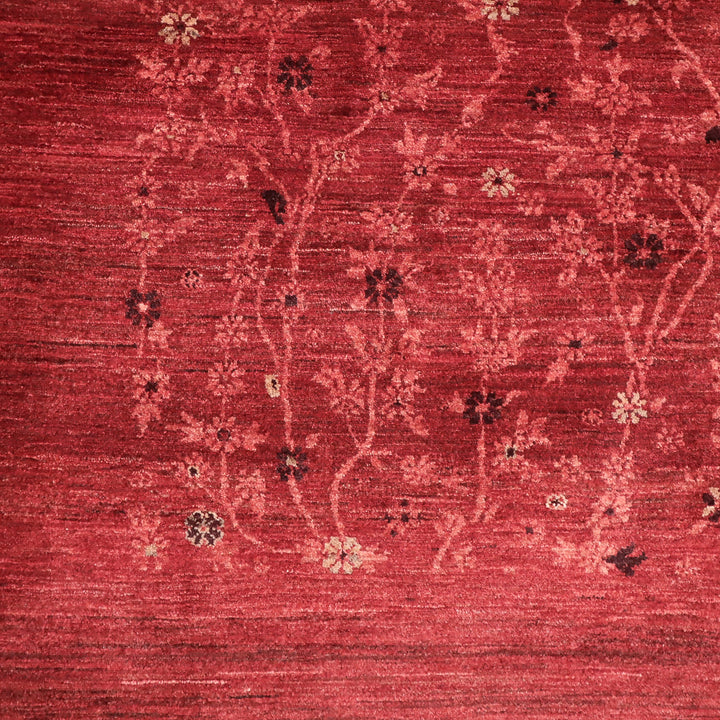 赤い背景に淡い色の枝と小花が織り込まれた繊細な模様の布地の一部。