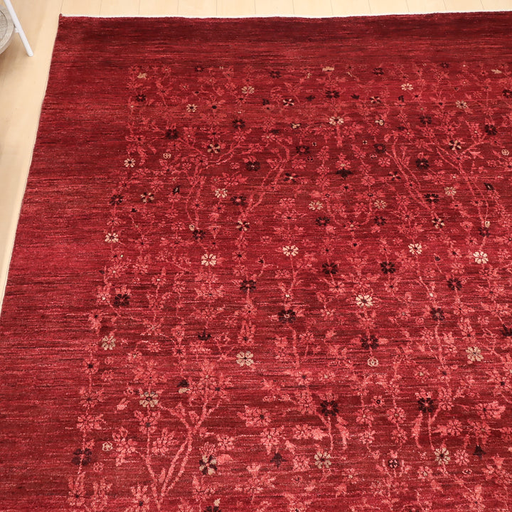 赤い地に様々な小さな花や葉の模様が織り込まれた繊細なデザインの敷物