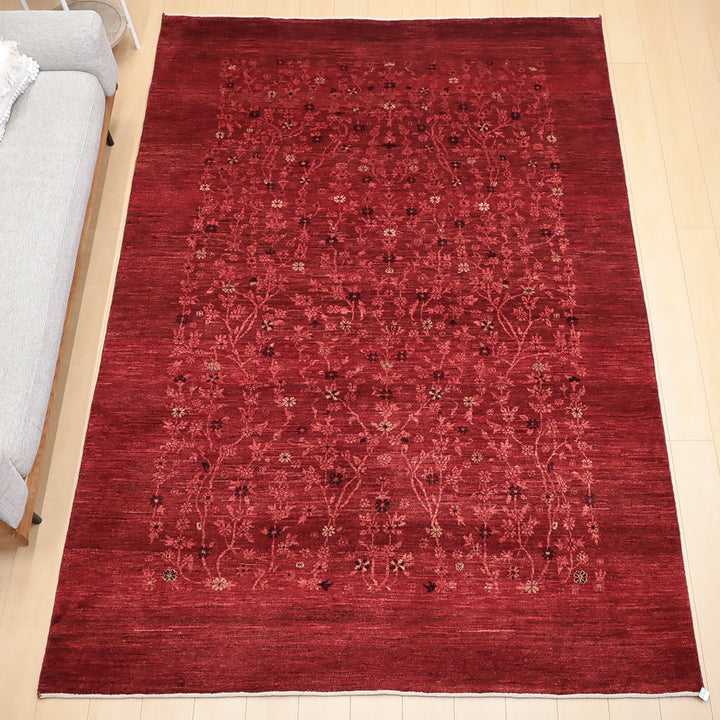 赤い地に繊細な花柄模様が広がるラグが明るい床に敷かれている様子。
